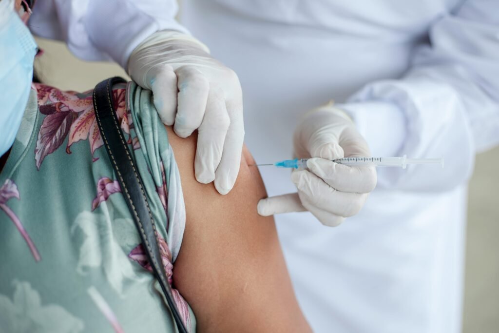 A healthcare worker administering a vaccine to a woman's shoulder.