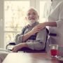 Senior patient in nursing home with helpful nurse in white uniform